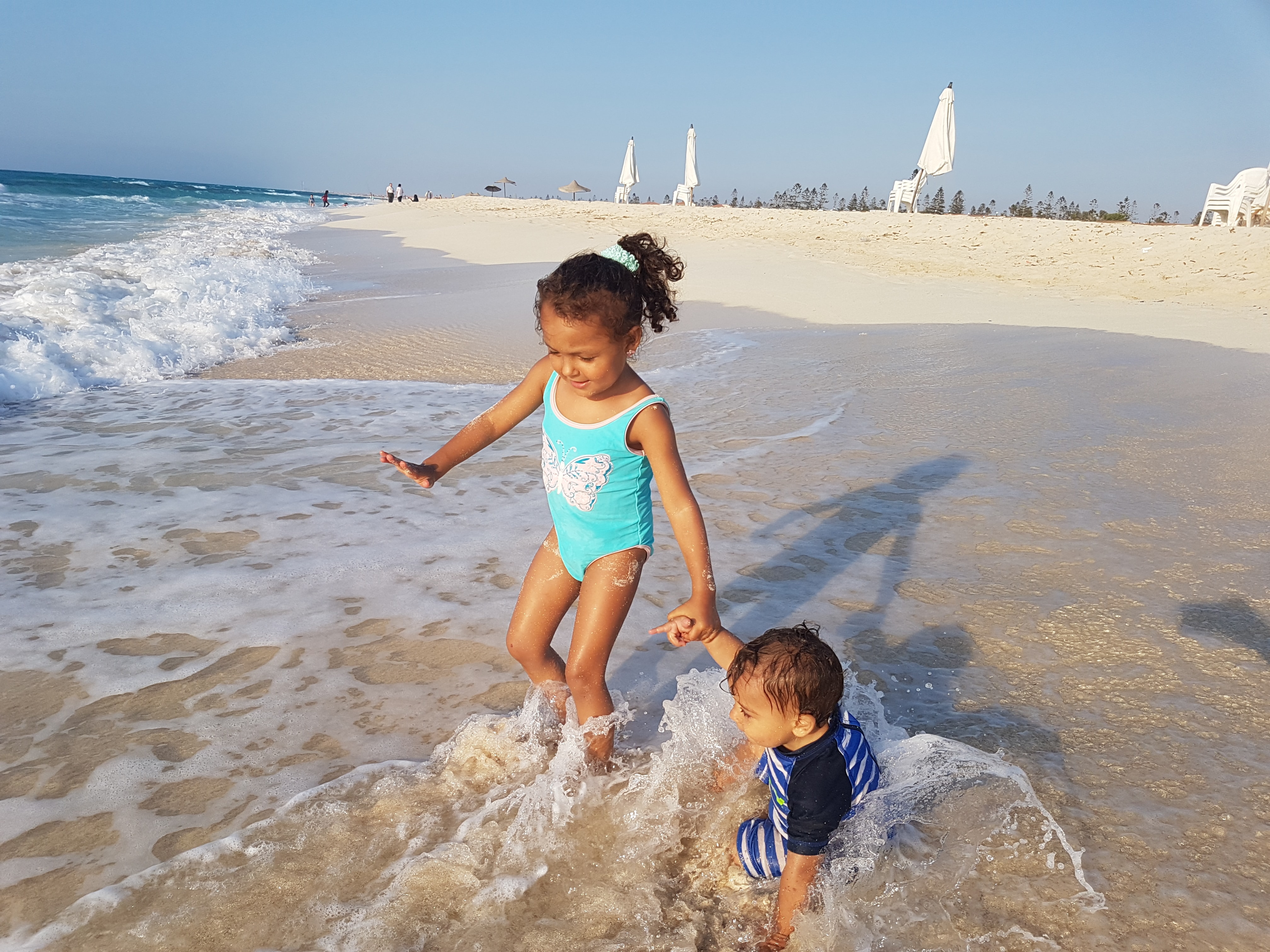 Kids playing in the surf on a white sand beach