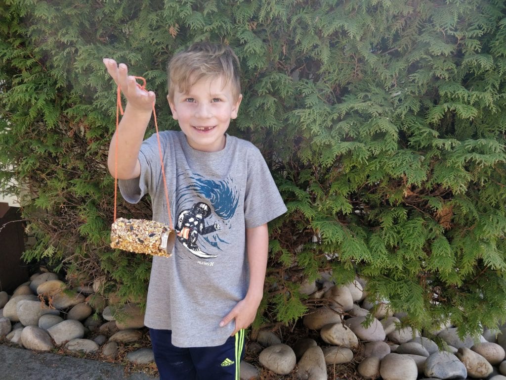 Smiling child showing off their DIY bird feeder