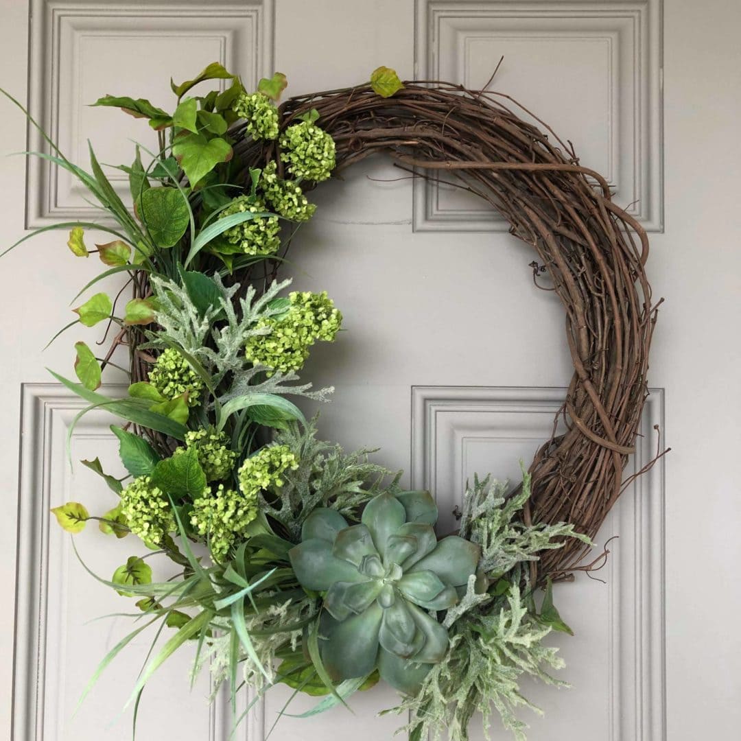 Greenery on a willow wreath on a white door