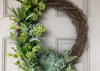 Greenery on a willow wreath on a white door