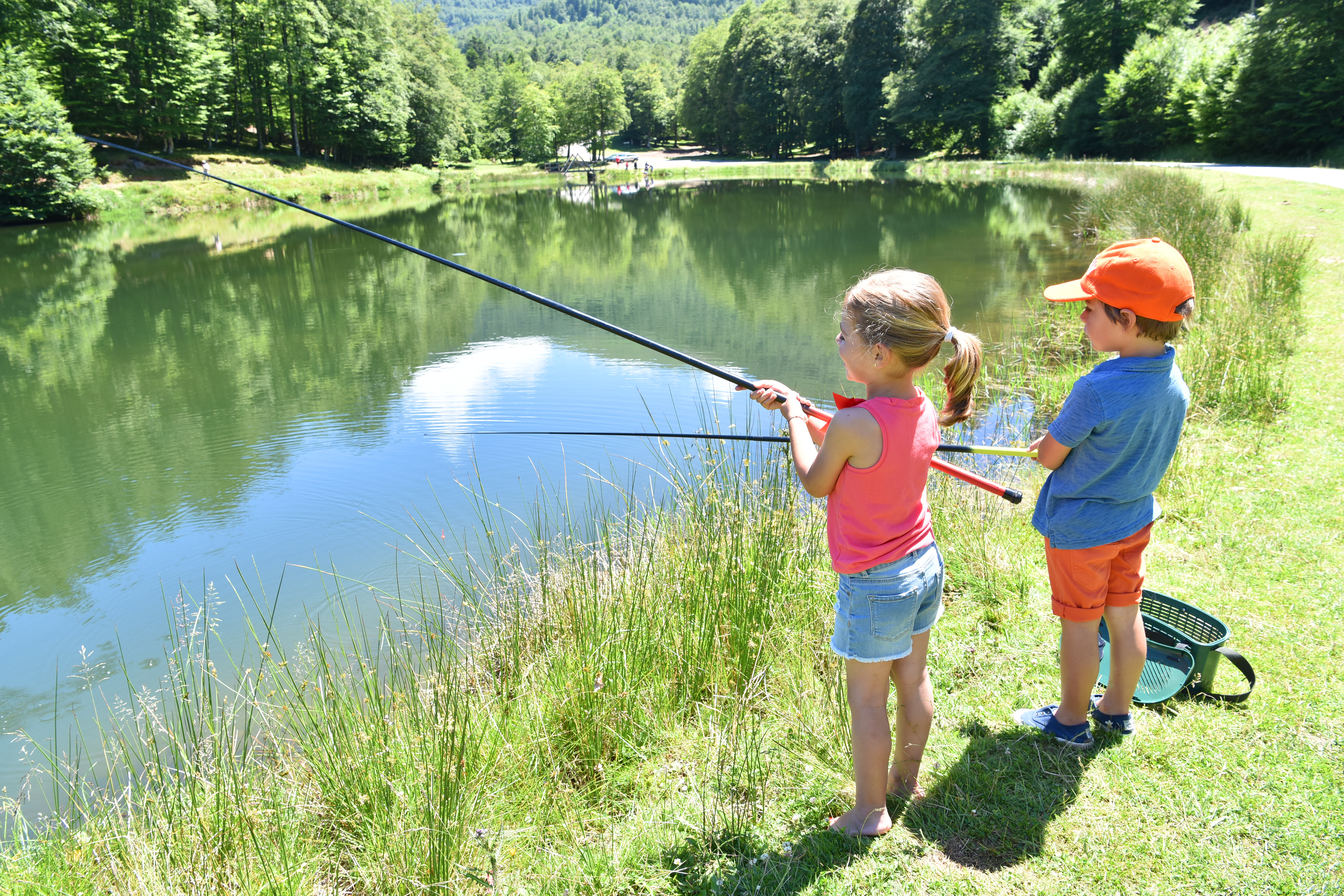 Kids fishing by mountain lake in summer