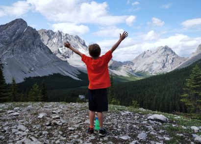 Kid raising arms in victory with mountains in the background