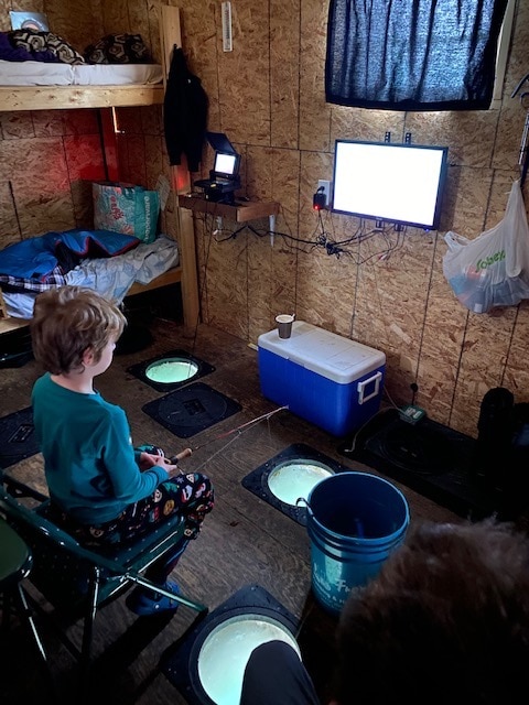 Child Ice Fishing inside an Ice fishing hut on Gull Lake, Alberta