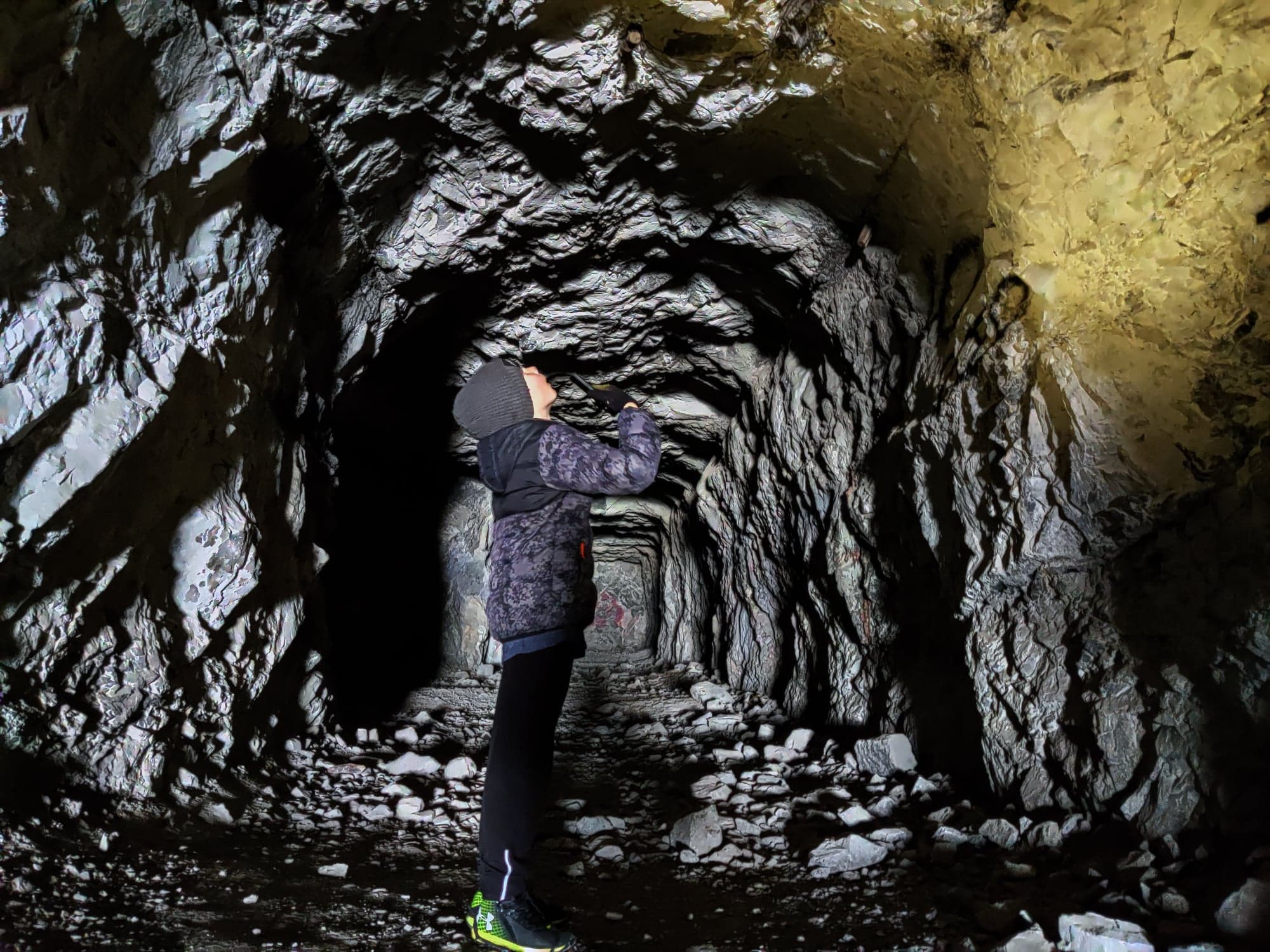 Boy in Heart Creek Bunker cave looking up in wonder at the spot he's shining a flashlight.