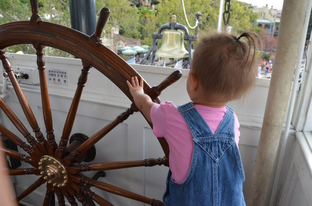 Toddler works the wheel on Mark Twain Riverboat in Disneyland